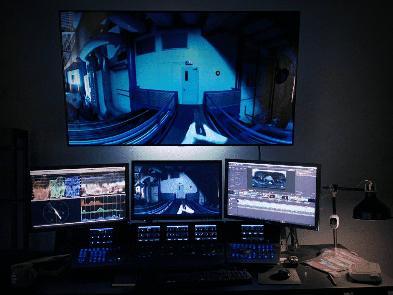 A color grading suite: monitors and a control surface in a dark room, a large screen showing a shot in progress